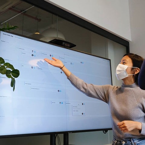 teacher with mask gesturing at screen